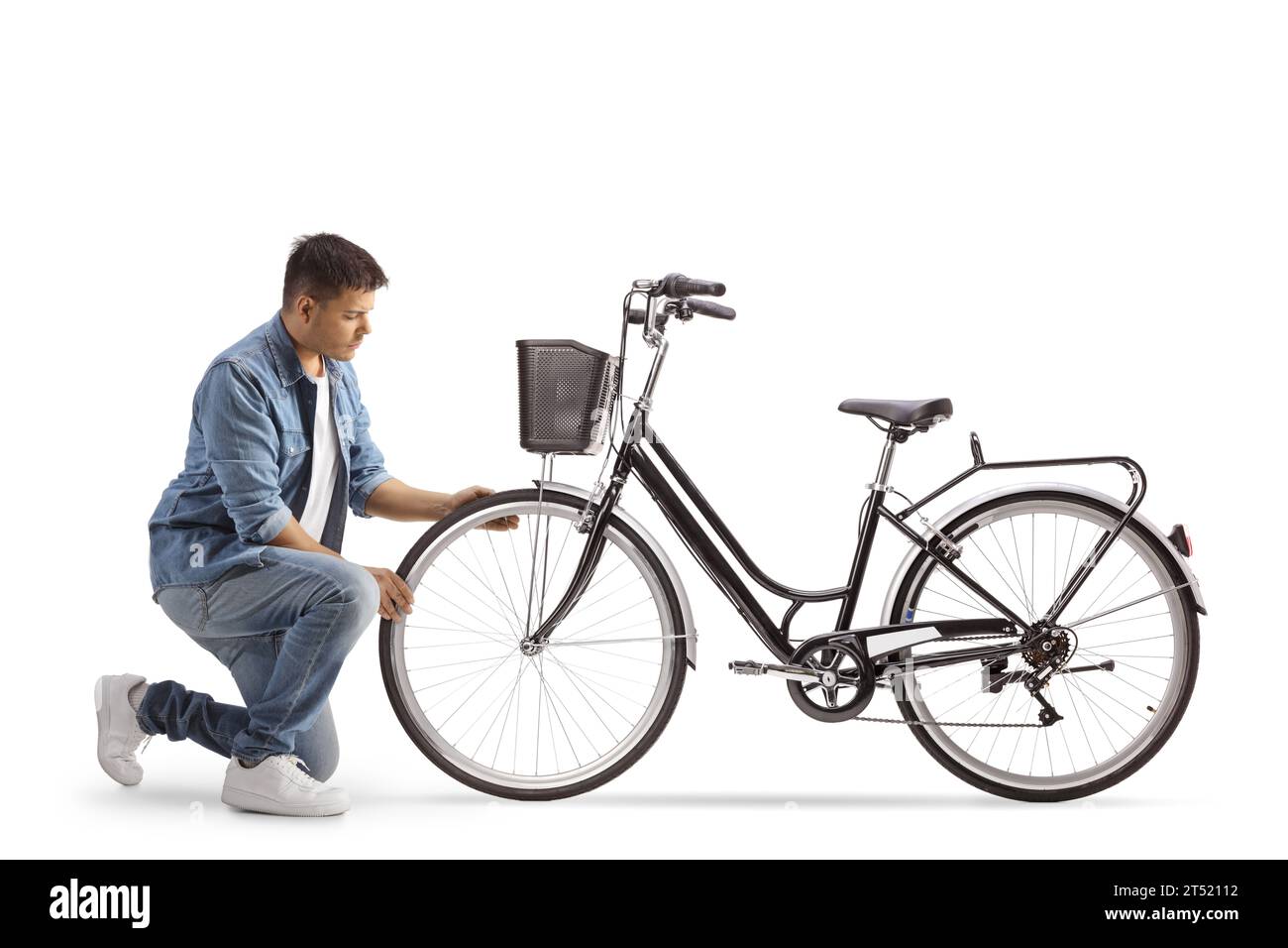 Jeune homme agenouillé et vérifiant roue de vélo isolé sur fond blanc Banque D'Images