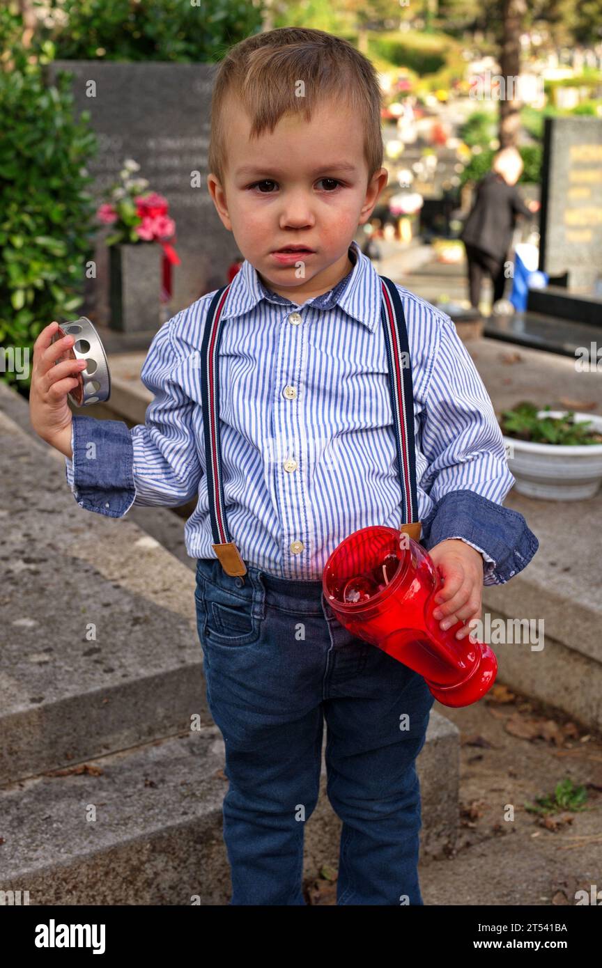 Petit enfant tenant une bougie sur la tombe Banque D'Images