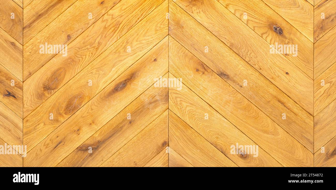 Un beau motif de parquet en bois de chêne clair étroitement posé en forme de chevrons avec des côtés symétriques. Banque D'Images