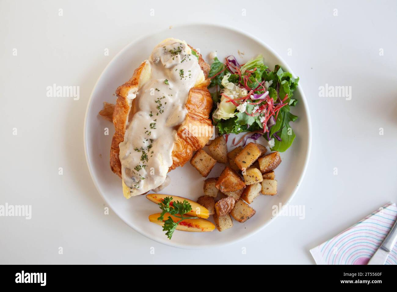 Sandwich au fromage à la crème aux champignons et aux croissants briochés aux œufs brouillés avec pêche, feta aux feuilles de roquette et pommes de terre sautées. Banque D'Images