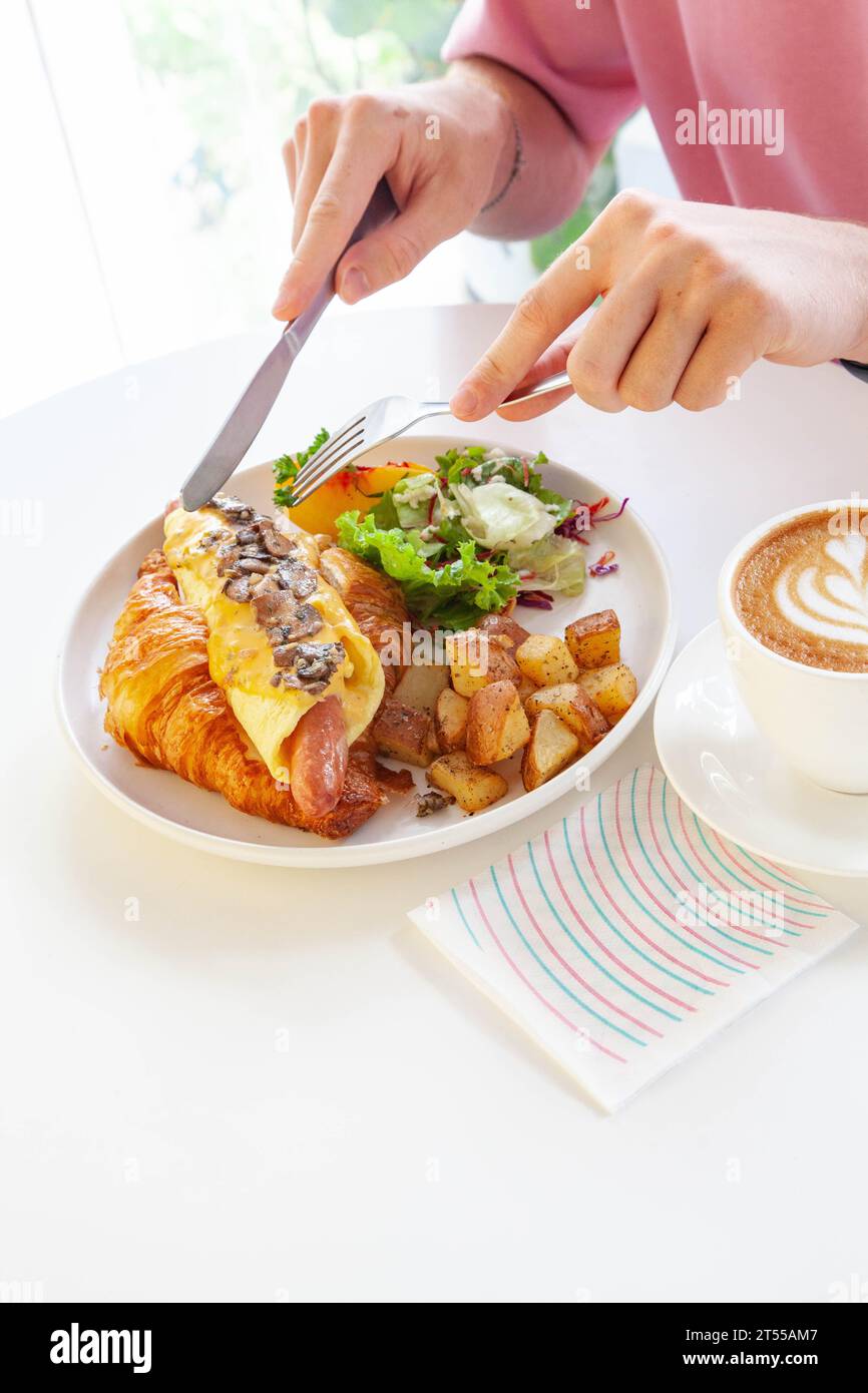 Sandwich brioche aux œufs croissants et saucisses avec fruits et légumes frais dans un café. Banque D'Images