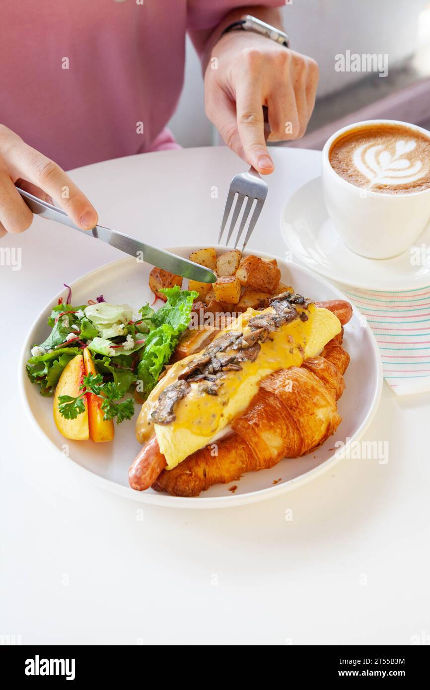 Sandwich brioche aux œufs croissants et saucisses avec fruits et légumes frais dans un café. Banque D'Images
