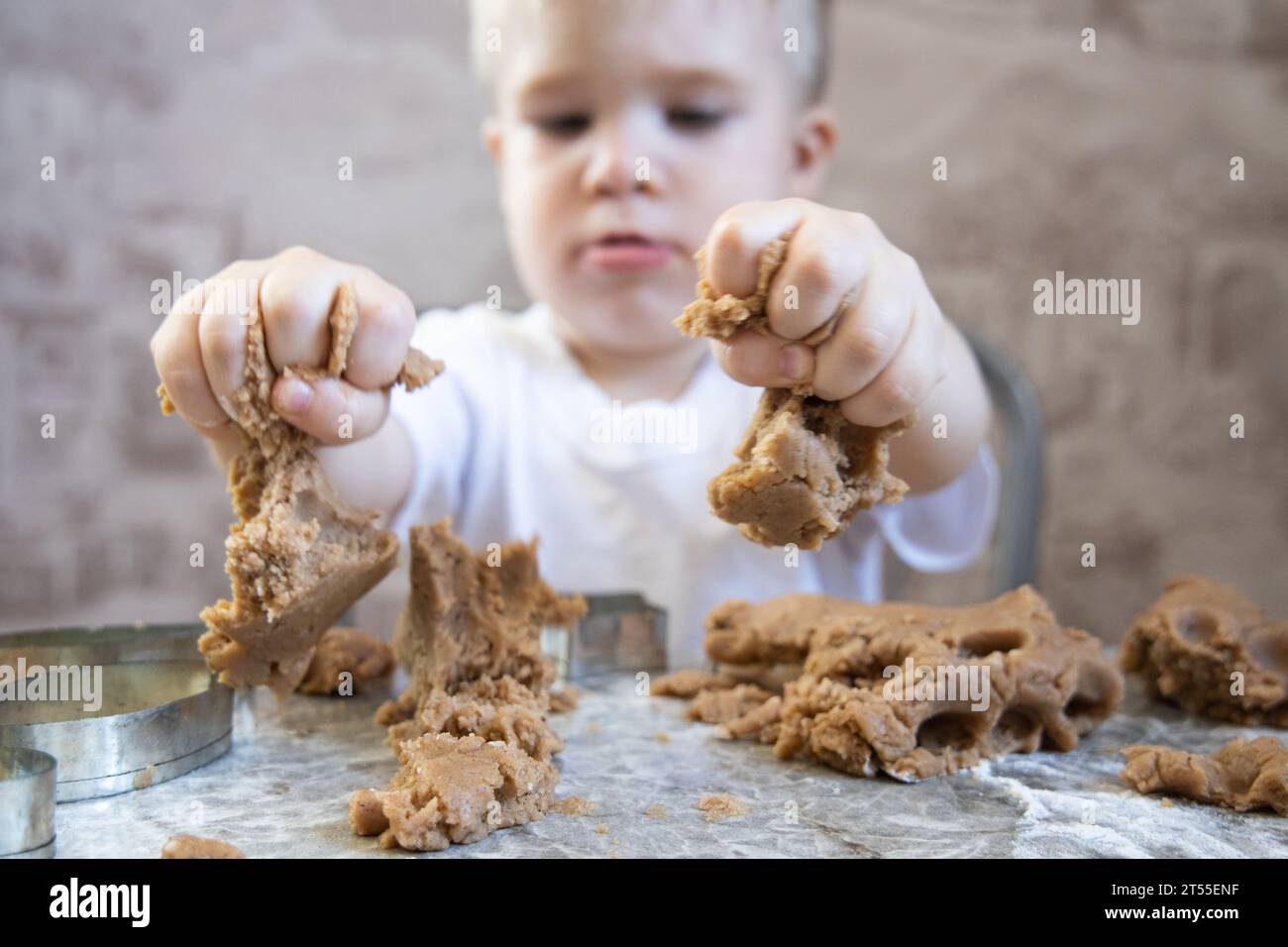 Le petit garçon pétrit la pâte pour les biscuits au gingembre Banque D'Images