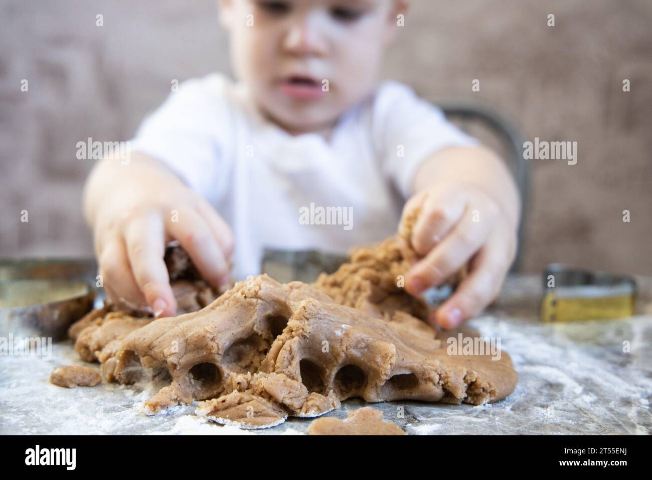 Le petit garçon pétrit la pâte pour les biscuits au gingembre Banque D'Images