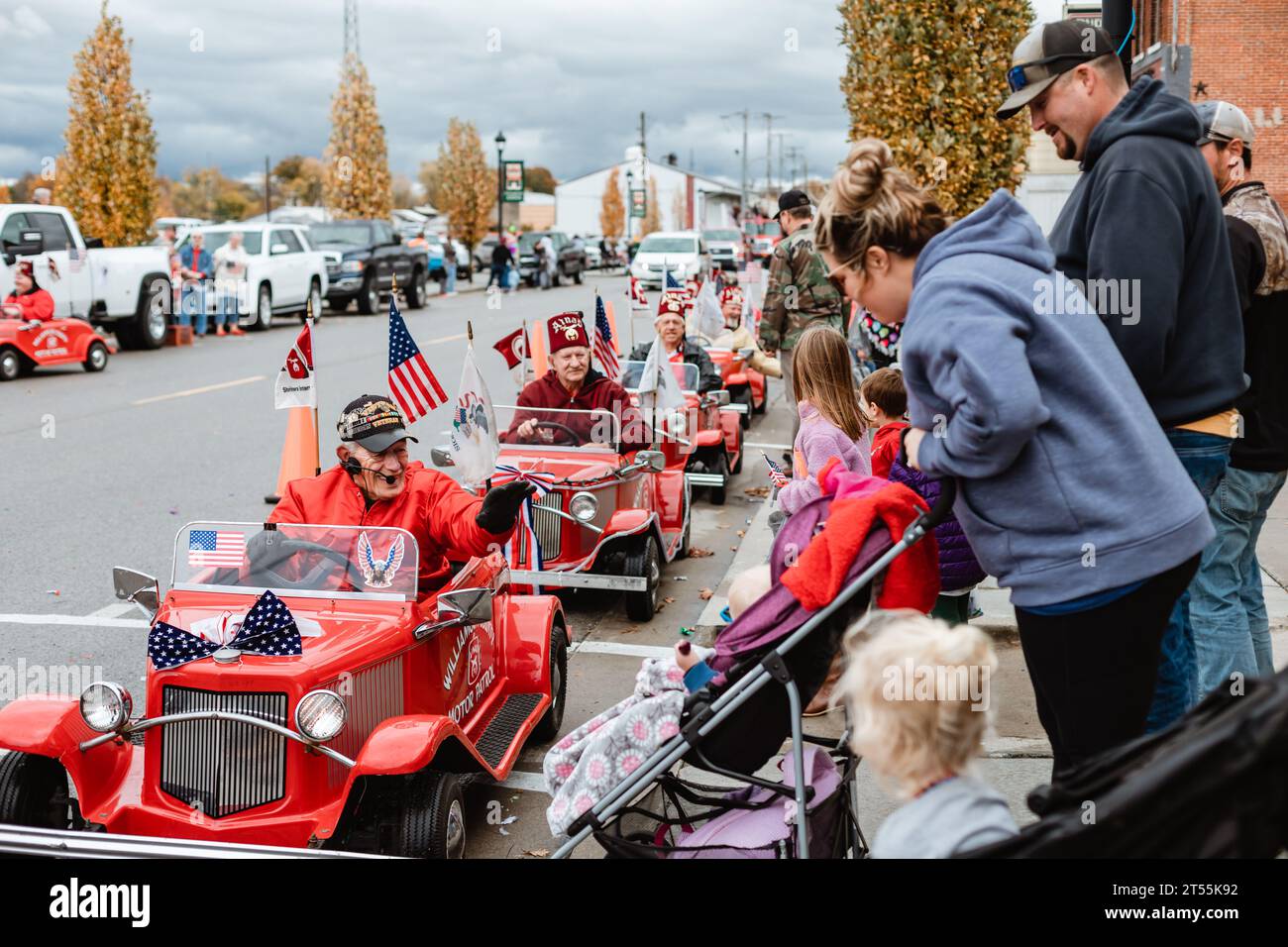 Les gens au défilé de la Journée des anciens combattants alors que Shriners conduisent des mini-voitures Banque D'Images