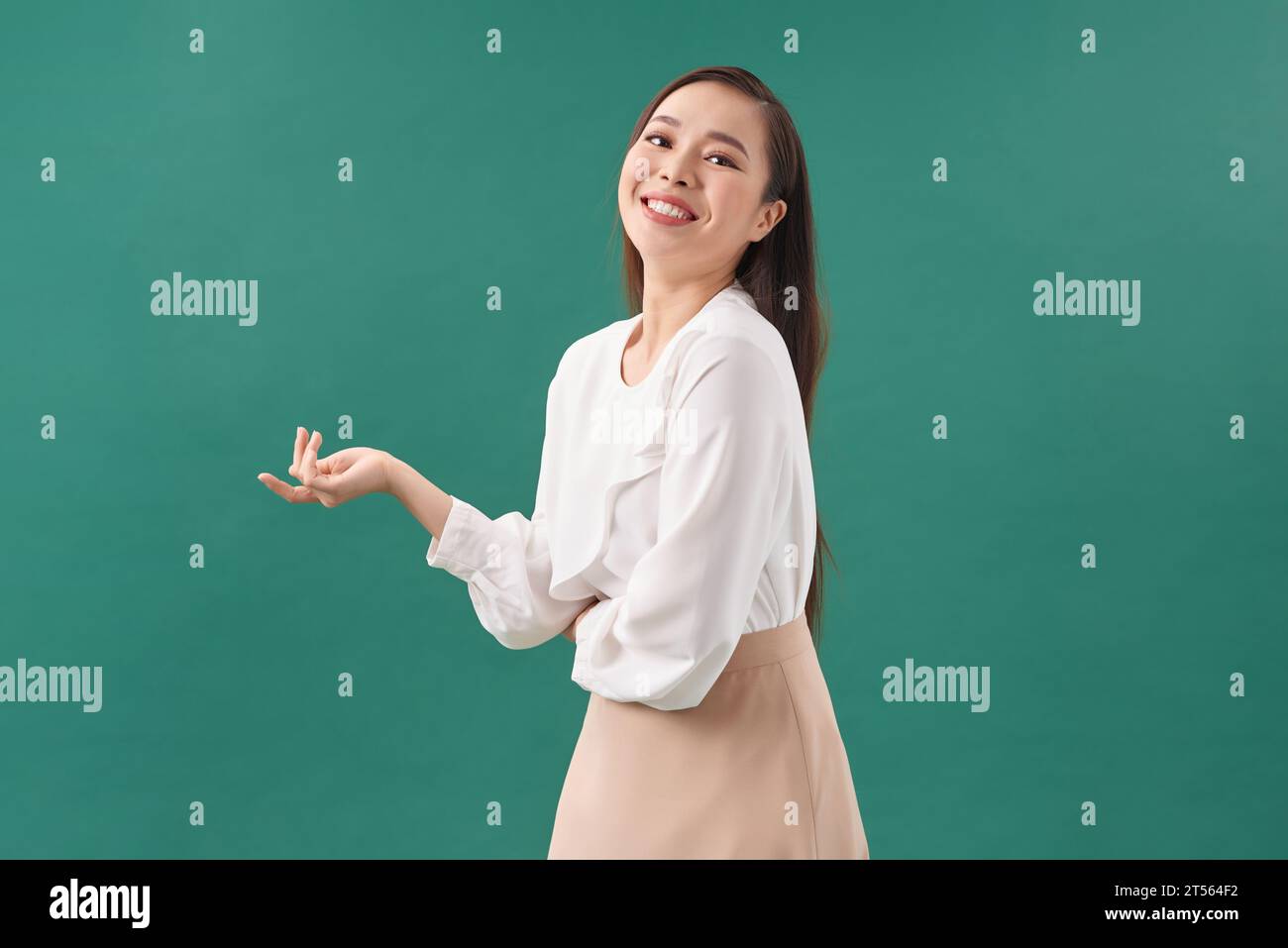 Modèle féminin asiatique souriant regardant up.Woman pointant les doigts loin sur fond blanc isolé. Banque D'Images