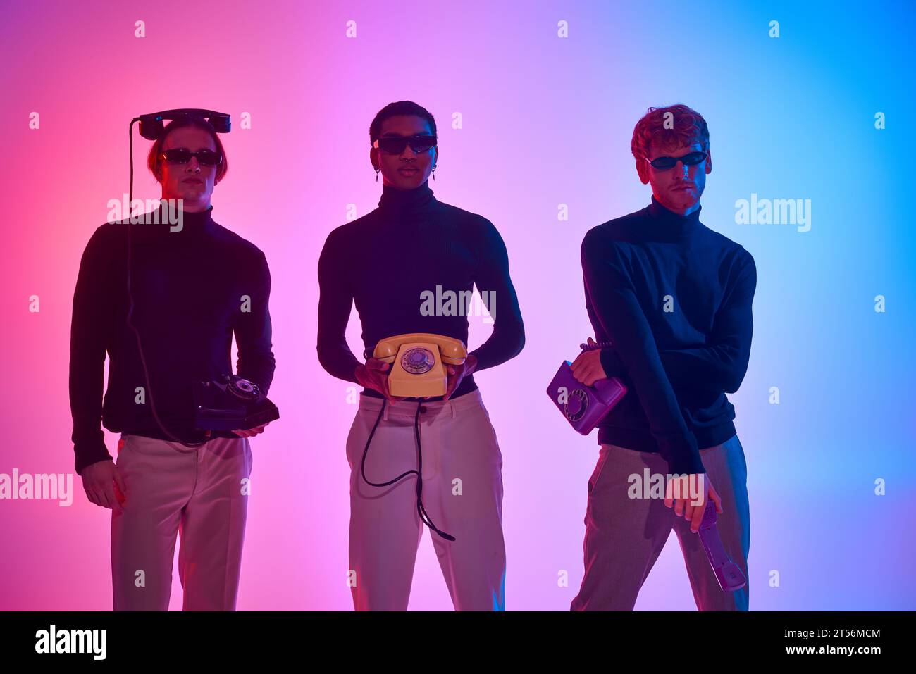 trois hommes multiethniques en tenues noires avec des téléphones fixes entourés de néons, mode Banque D'Images
