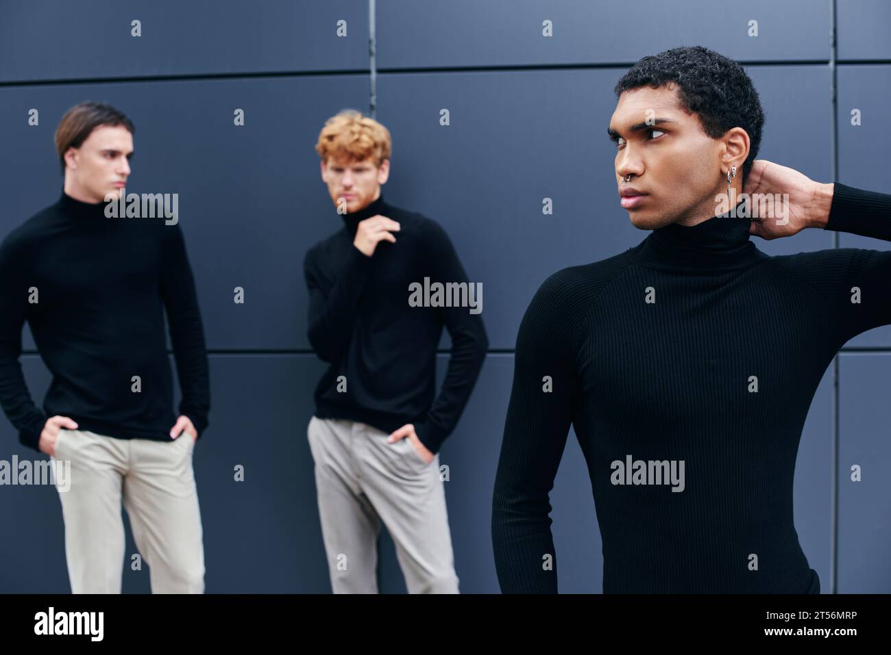 trois jeunes hommes multiraciaux dans des tenues décontractées élégantes debout par le mur, concept de mode Banque D'Images