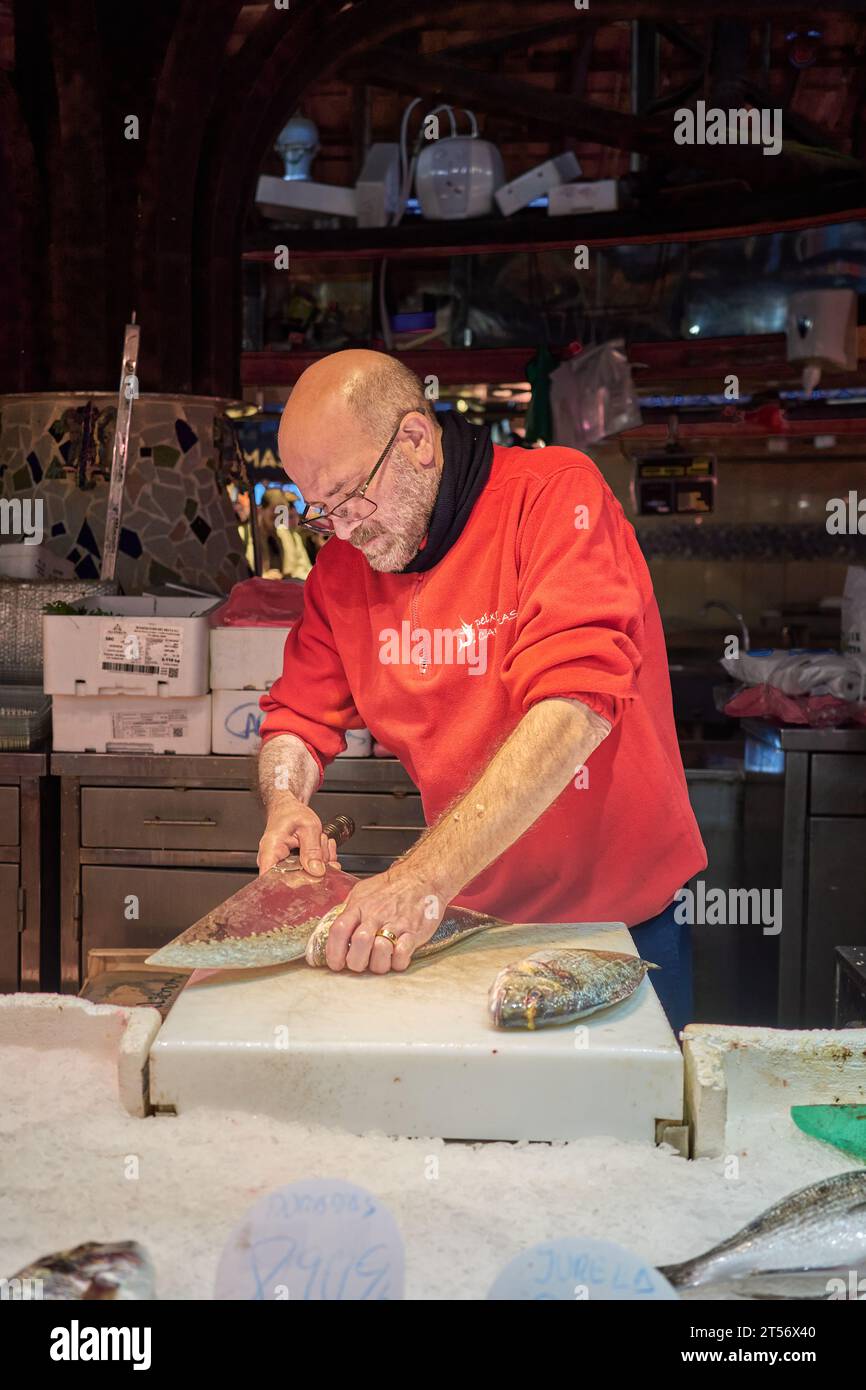 Un poissonnier prépare du poisson au marché de la Boqueria au large de Las Ramblas à Barcelone, en Espagne. Banque D'Images