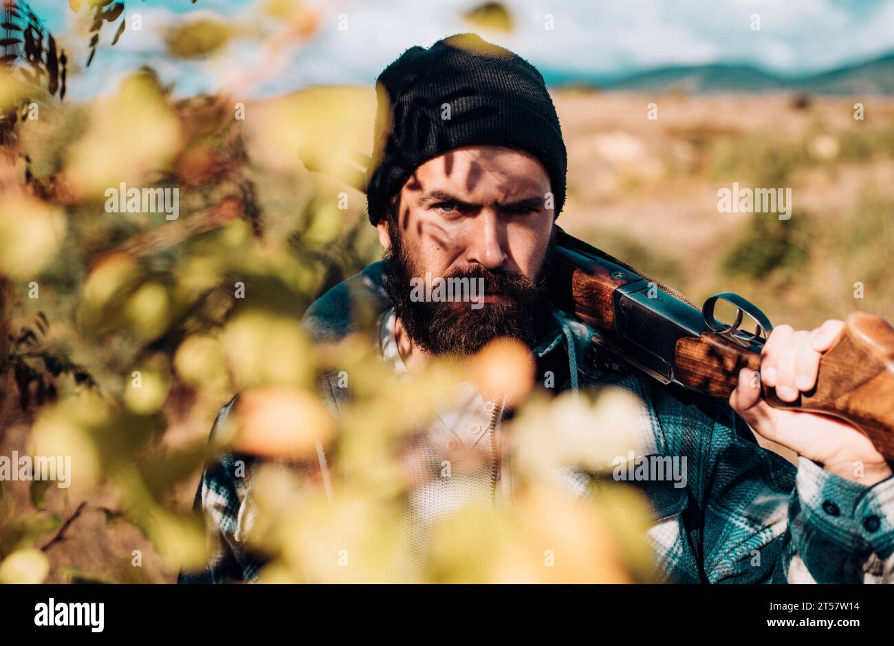 Chasseur barbu tenant une arme à feu et marchant dans la forêt. Chasseur avec fusil de chasse. Gros plan Portrait de Hamdsome Hunter. Banque D'Images