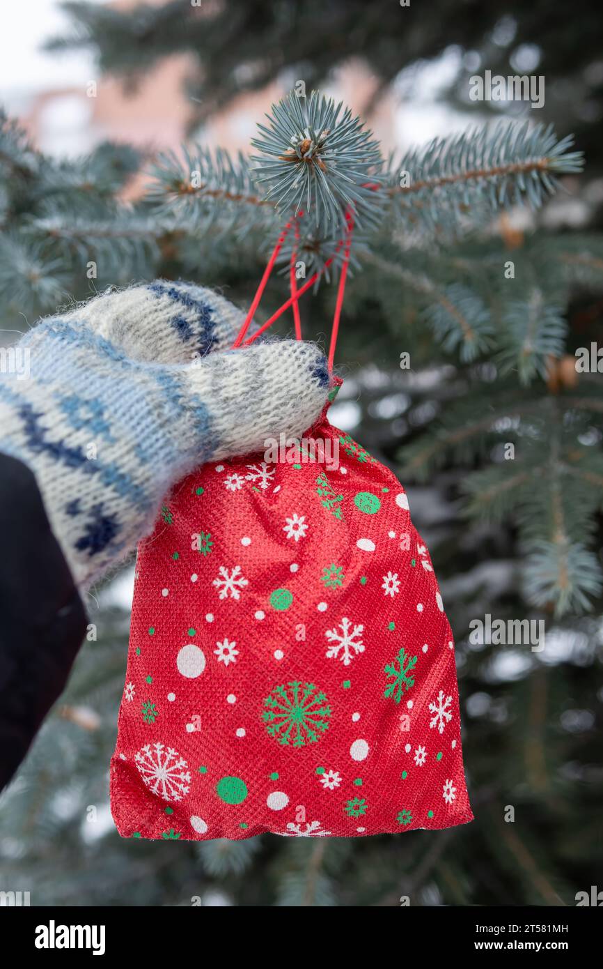Cadeau de Noël rouge est accroché sur l'arbre de pin à l'extérieur. Le concept de vacances et de vacances d'hiver Banque D'Images