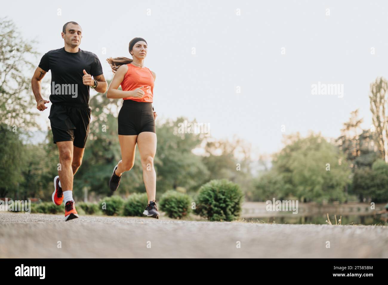 Deux coureurs bien construits faisant du jogging dans le parc, s'entraînant en plein air ensemble. Banque D'Images