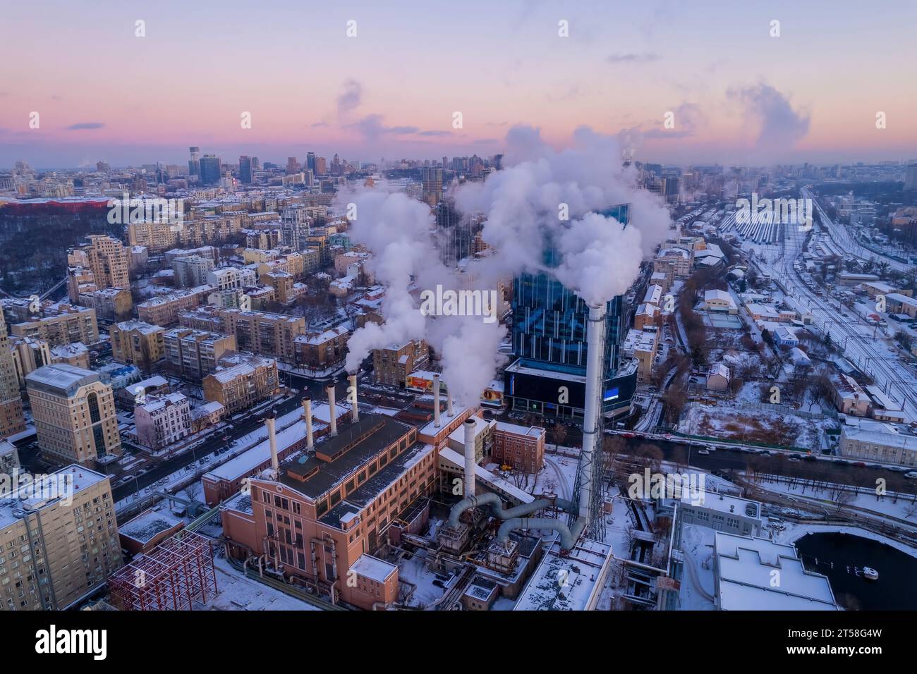 De la fumée s'échappe du tuyau de la chaudière. Système de chauffage central des immeubles d'appartements. Coucher de soleil en hiver Banque D'Images