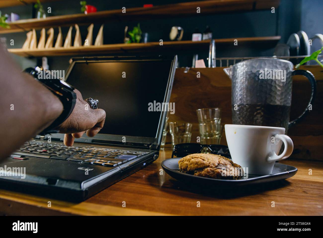 Gros plan de la main d'un homme noir méconnaissable debout travaillant à taper sur un ordinateur portable au-dessus du bar à l'intérieur du restaurant, concept de technologie, espace de copie. Banque D'Images