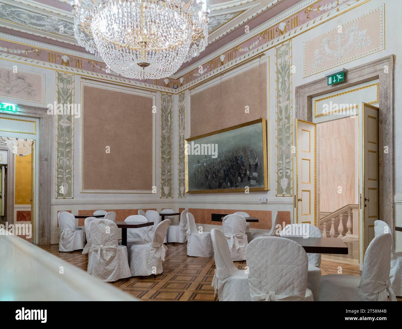 Salle de réception au théâtre la Fenice à Venise, Italie. Des chaises enveloppées de tissu entourent les tables. Banque D'Images