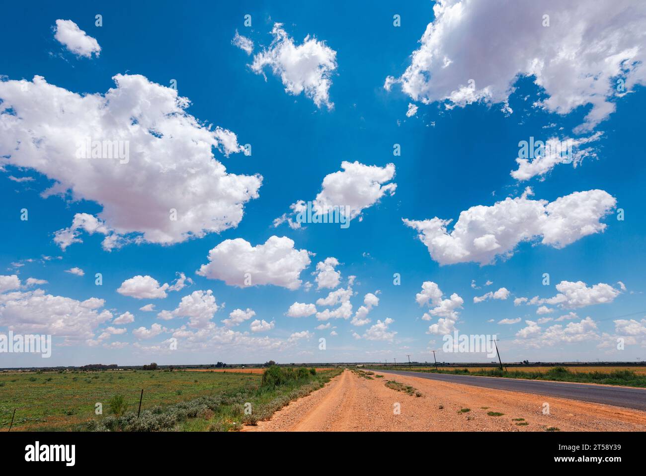 Nuages blancs légers parmi un ciel bleu vif au-dessus d'une route principale au-dessus d'une route rurale en Afrique du Sud Banque D'Images