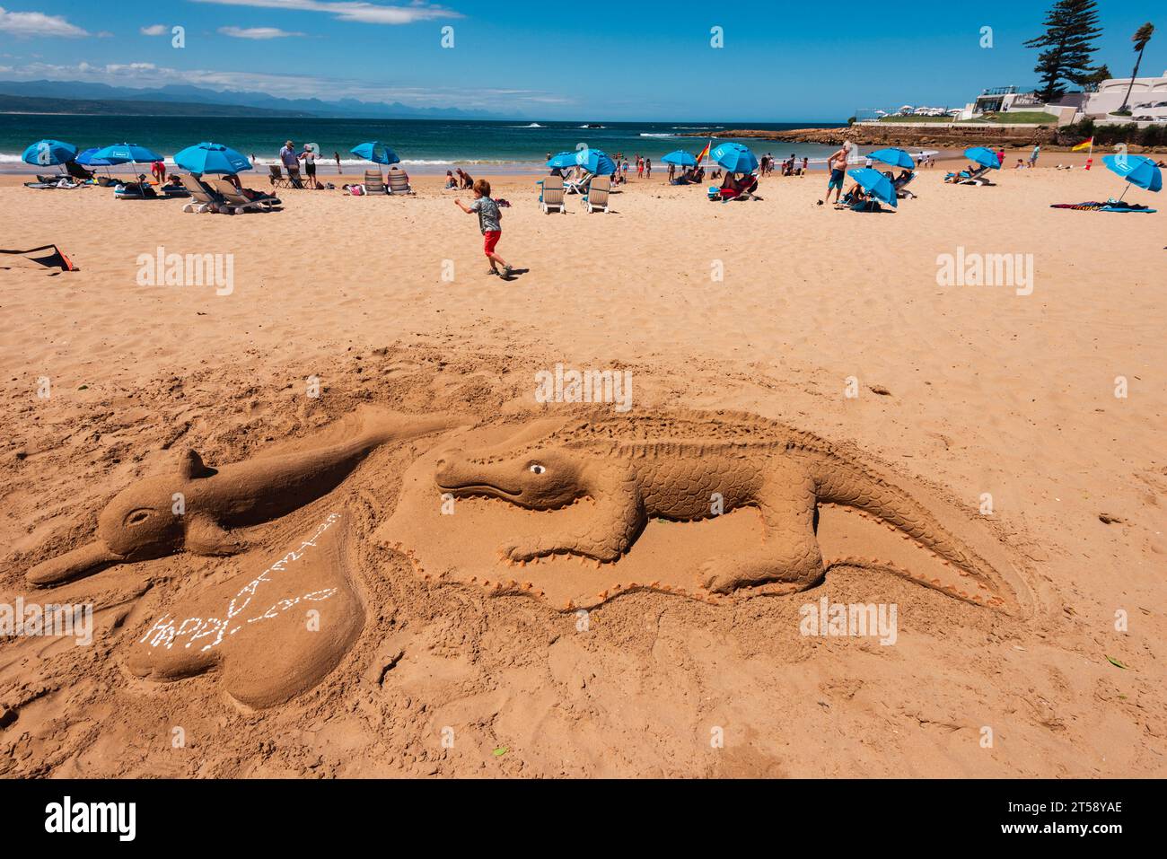 Un crocodile et dauphin de château de sable sur une plage animée de Plettenberg Bay en Afrique du Sud Banque D'Images
