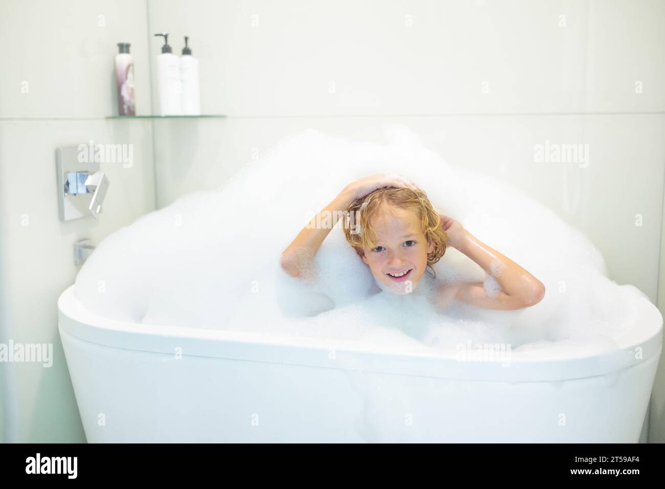 Enfant jouant avec de la mousse de savon dans le bain. Petit garçon se baignant et se lavant les cheveux avec du shampooing pour enfants. Hygiène et routine de coucher pour les enfants. Banque D'Images