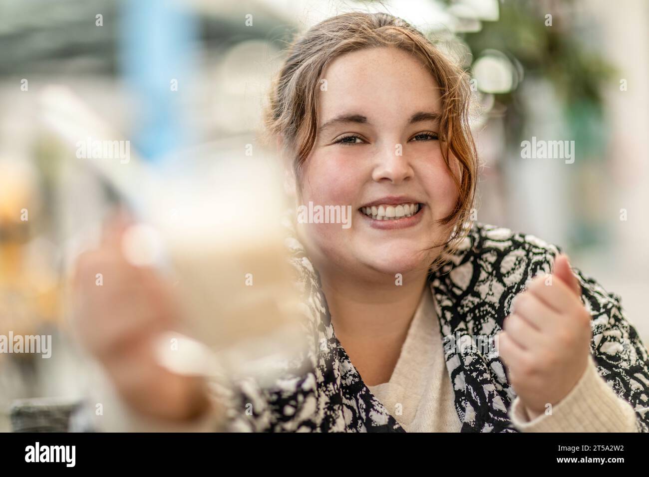 Une jeune femme de plus grande taille appréciant un verre dans un café en plein air Banque D'Images