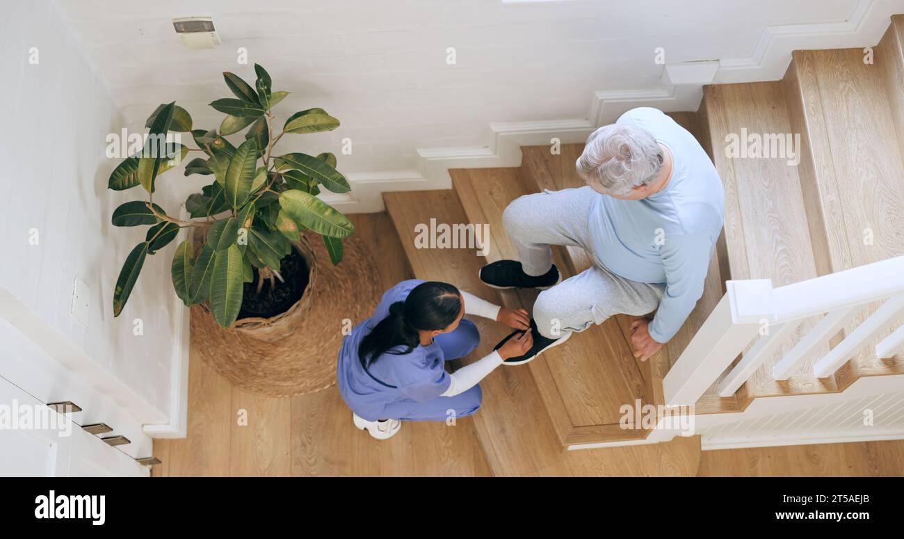 Chaussures de cravate infirmière de l'homme âgé sur les escaliers à la maison, aide et vue de dessus du soutien. Soignant attachant les baskets de la personne âgée d'en haut, l'assistance et Banque D'Images