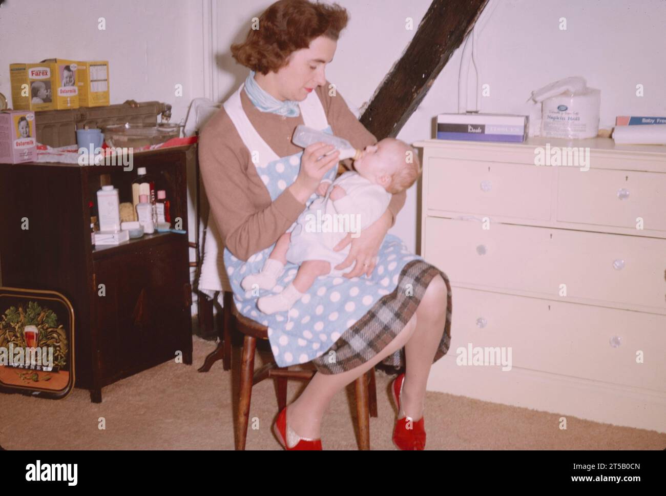 Mère nourrissant le biberon bébé 1960s. Banque D'Images