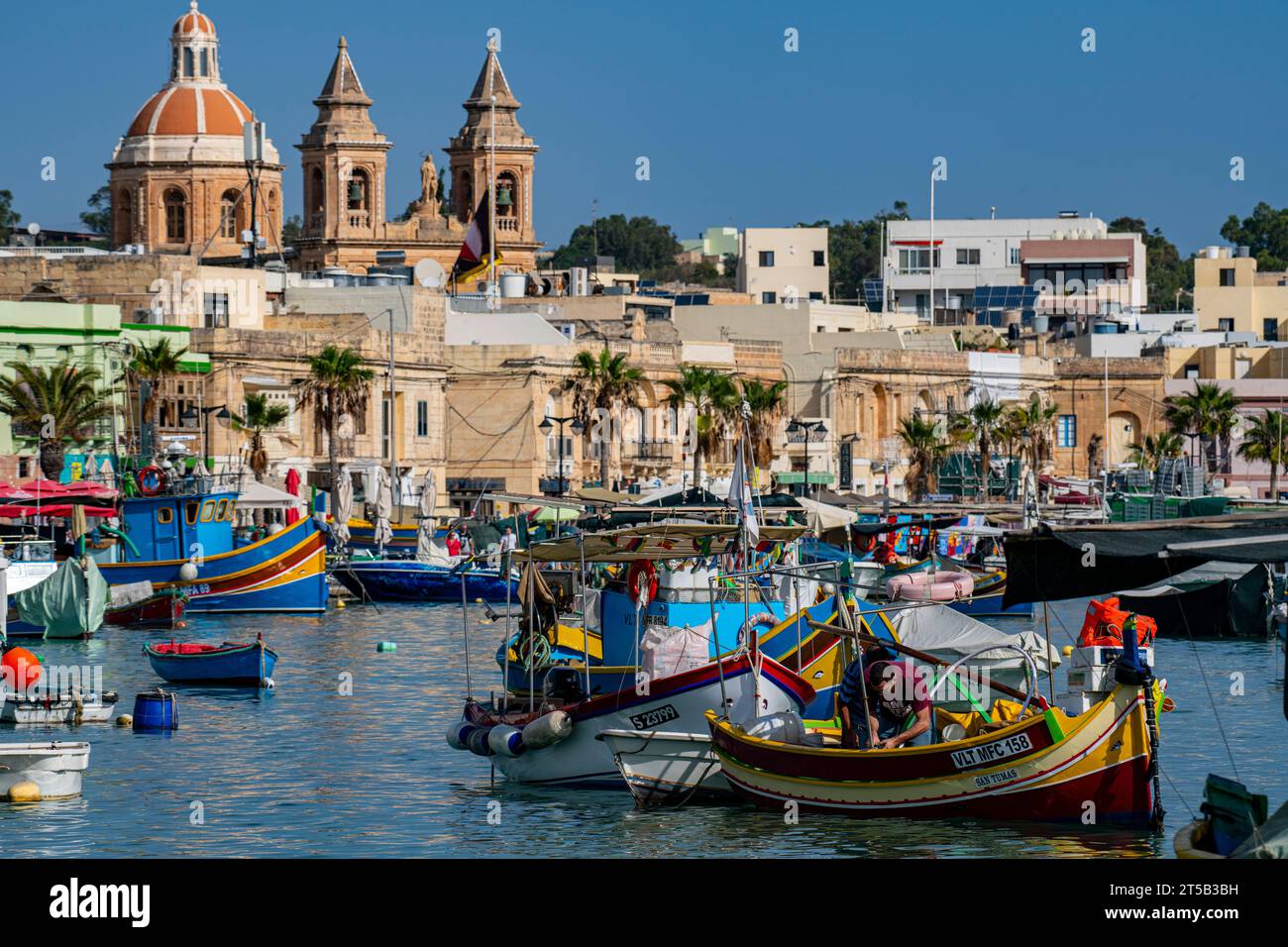 Les bateaux colorés dans le port de Marsaxlokk et l'église notre-Dame. Malte Banque D'Images