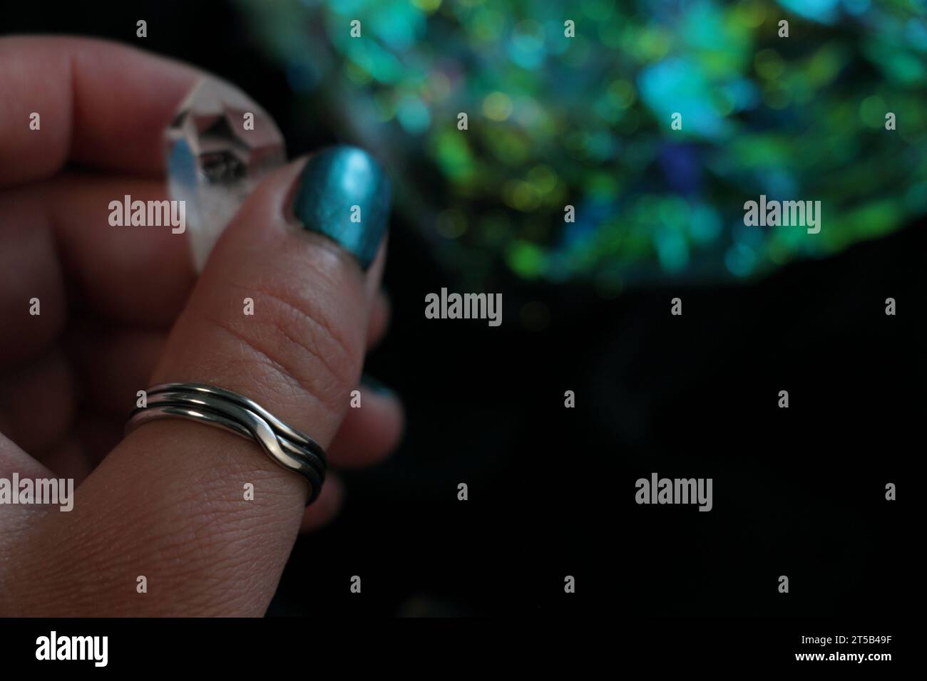 Main de femme avec des ongles polis et bague spéciale en argent tenant un cristal Banque D'Images