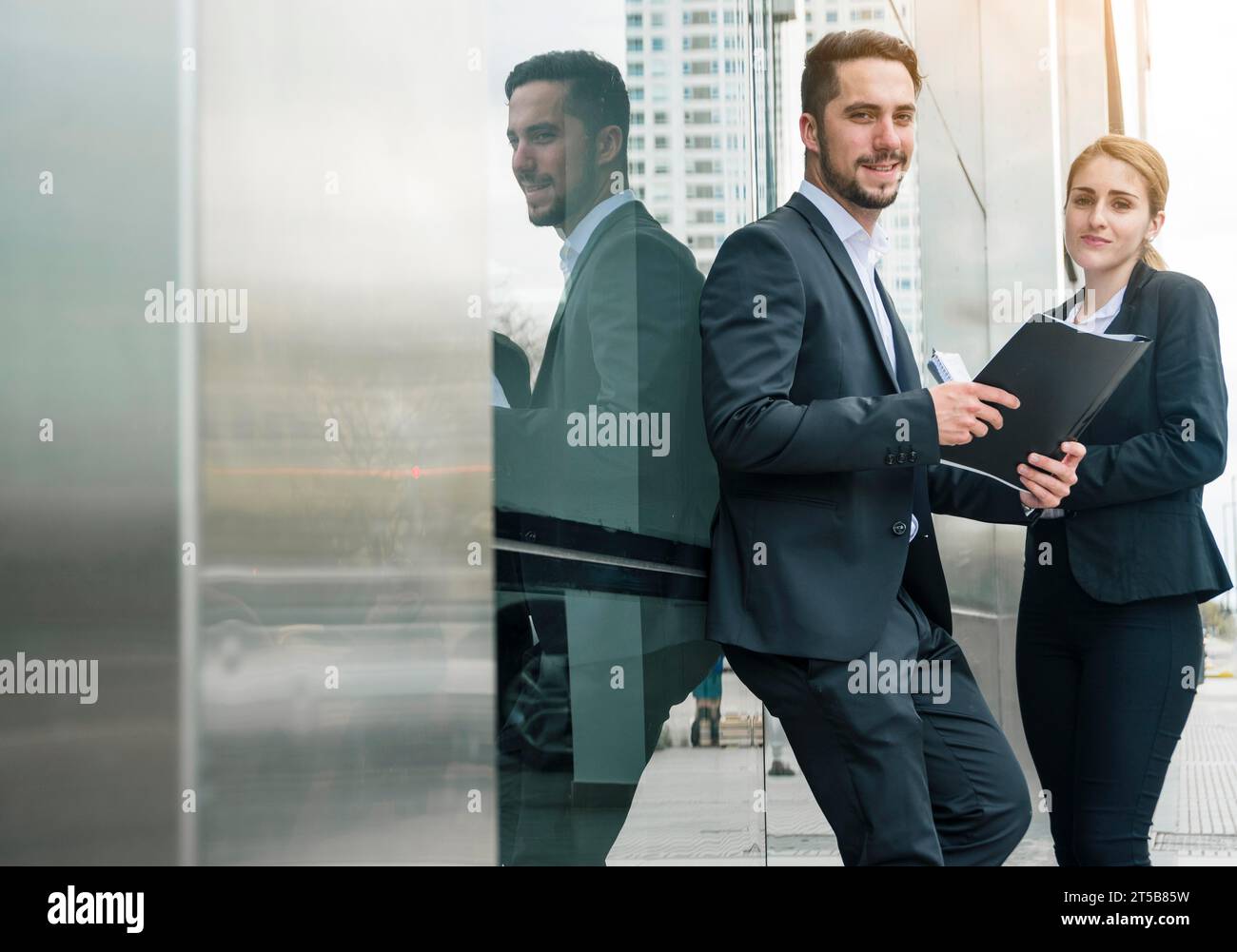 Portrait jeune homme d'affaires tenant le dossier main debout avec sa collègue féminine s à l'extérieur Banque D'Images