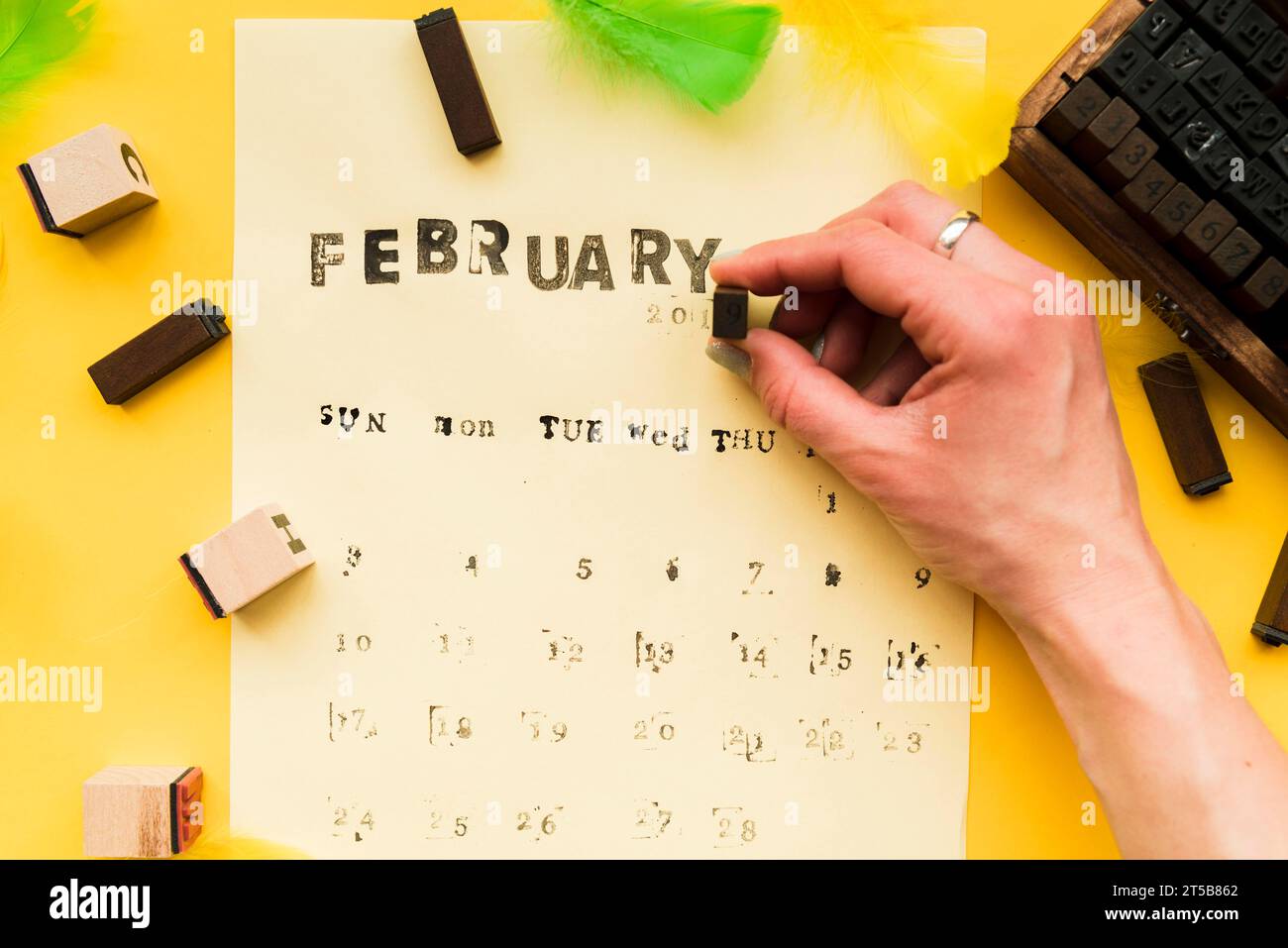Personne faisant le calendrier de février avec des blocs typographiques fond jaune Banque D'Images