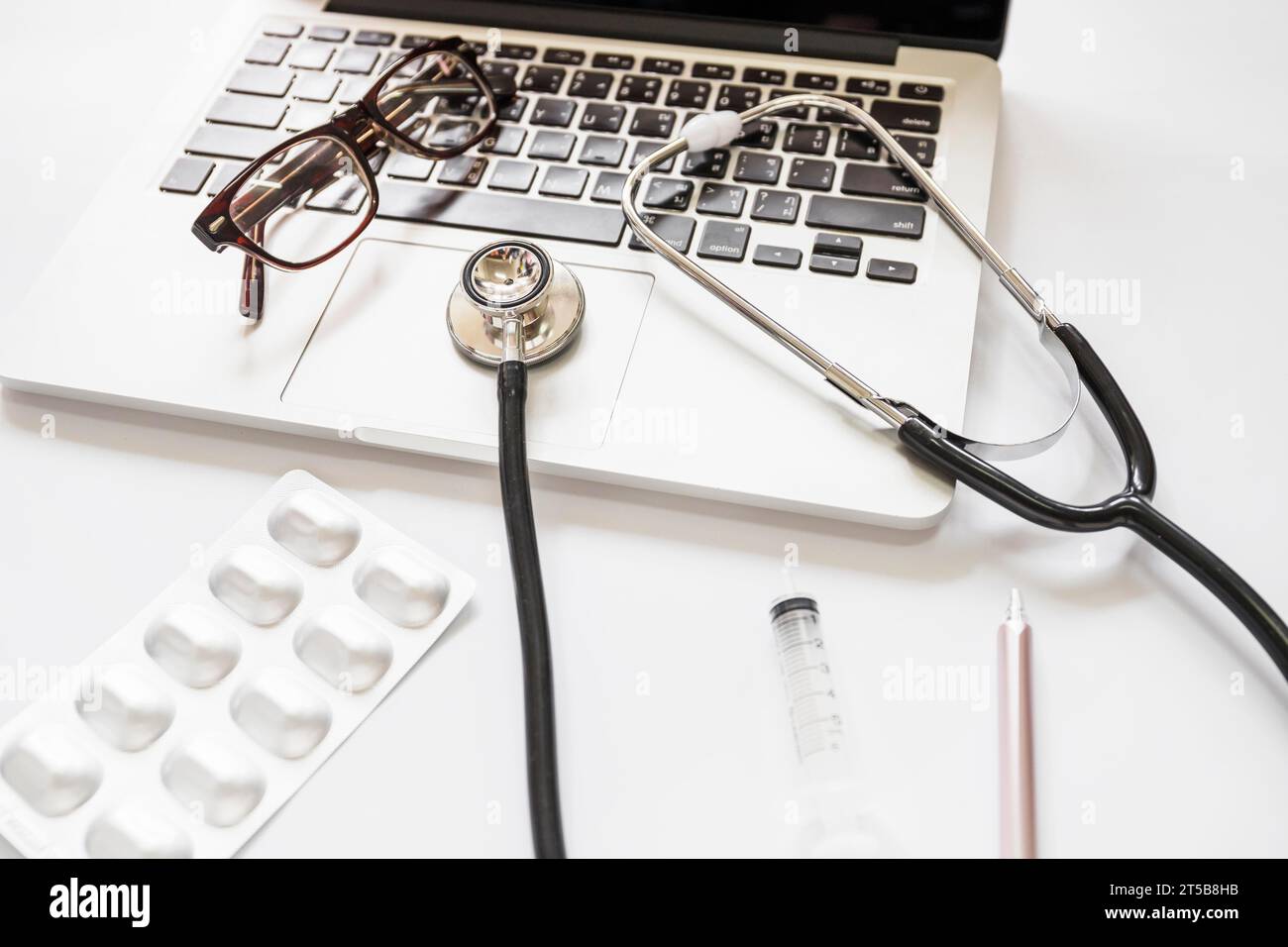 Clavier d'ordinateur portable de lunettes de stéthoscope avec fond blanc de stylo de seringue de paquet de médicament Banque D'Images