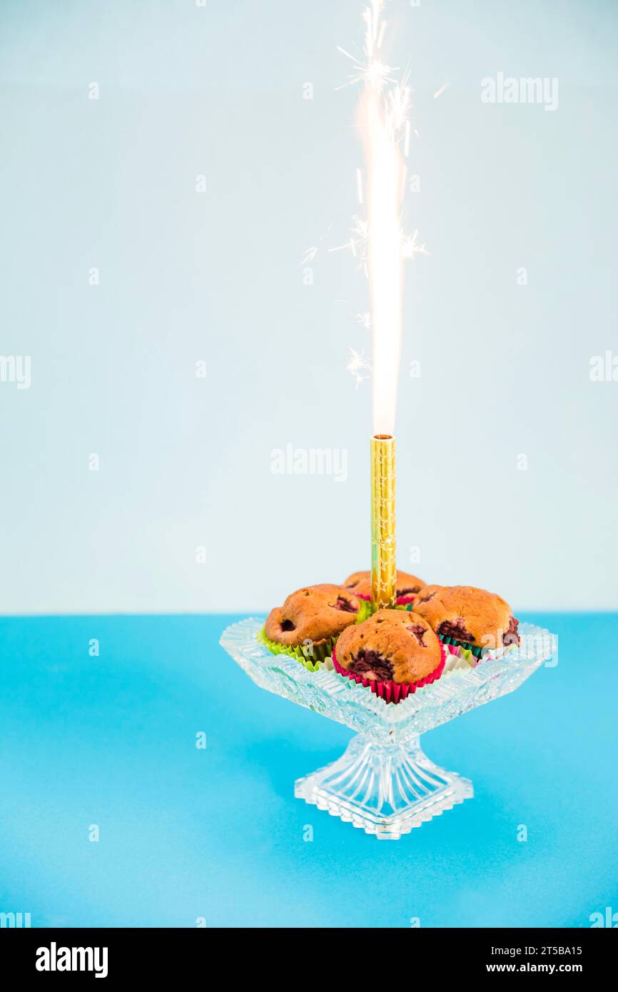 Feu d'artifice étincelant moyen cupcake cakestand transparent sur fond rose Banque D'Images