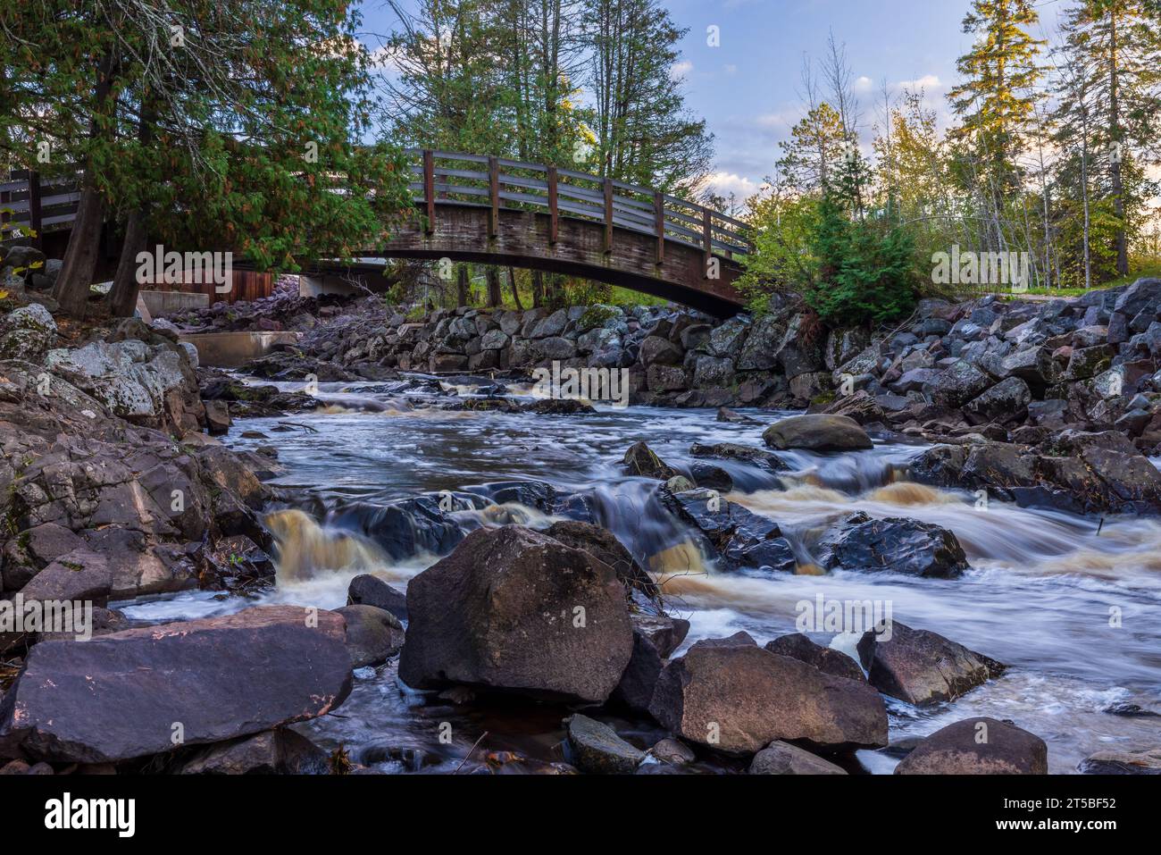 Une passerelle au-dessus d'une rivière dans les bois pendant l'automne. Banque D'Images