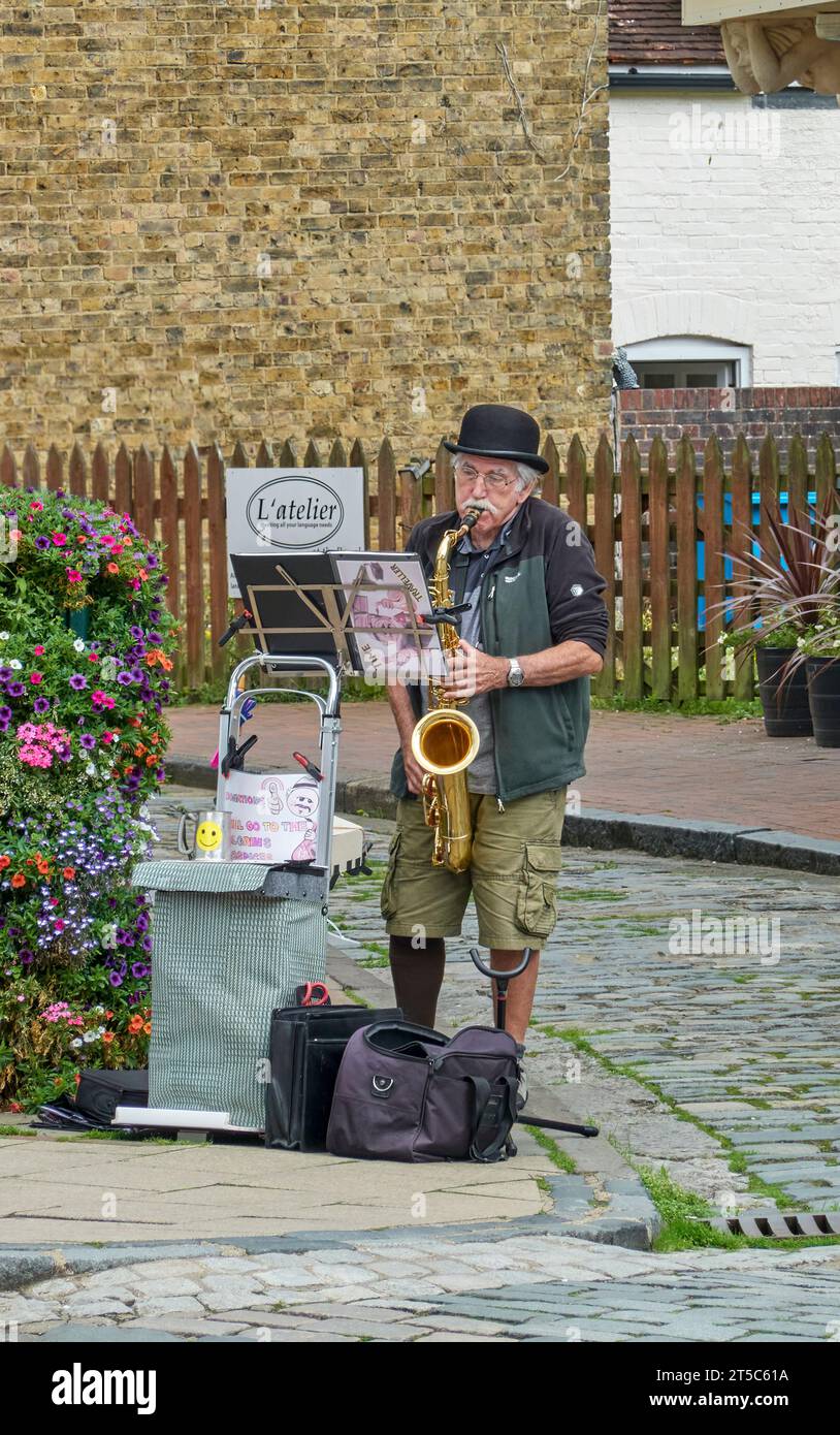 Busker de rue portant un chapeau melon jouant du saxophone dans Faversham Banque D'Images