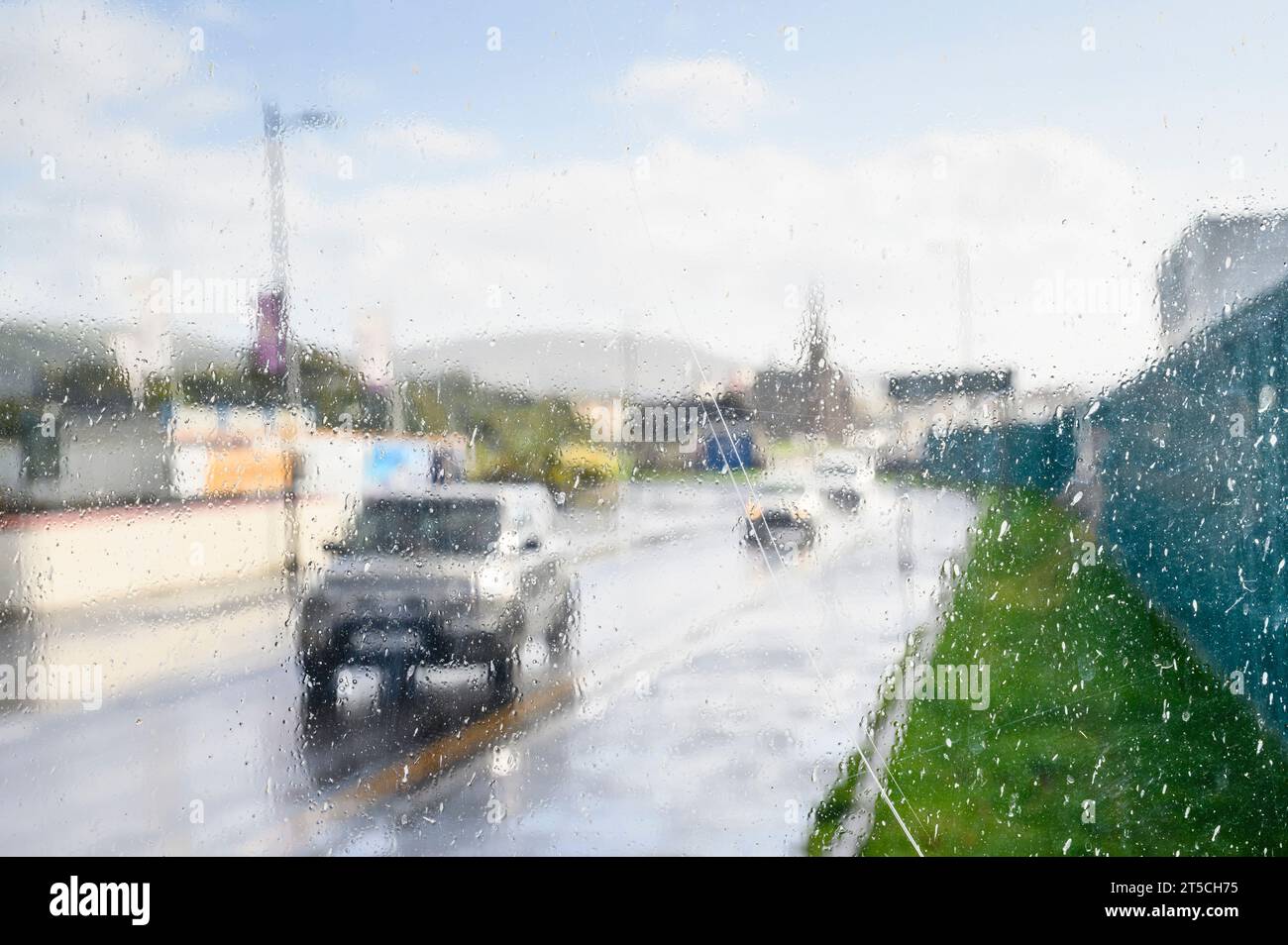 Vue floue regardant à travers une fenêtre d'abri à des voitures conduisant sous une douche de pluie, Royaume-Uni Banque D'Images
