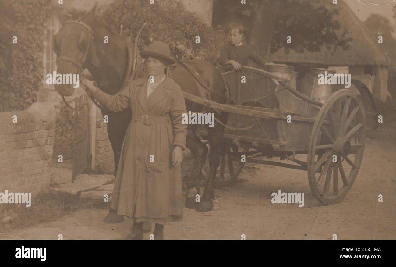 Milk Round : photographie de la première Guerre mondiale d'une femme conduisant un cheval et une charrette. Le chariot contient un petit garçon et plusieurs grosses barquettes de lait pour la livraison Banque D'Images