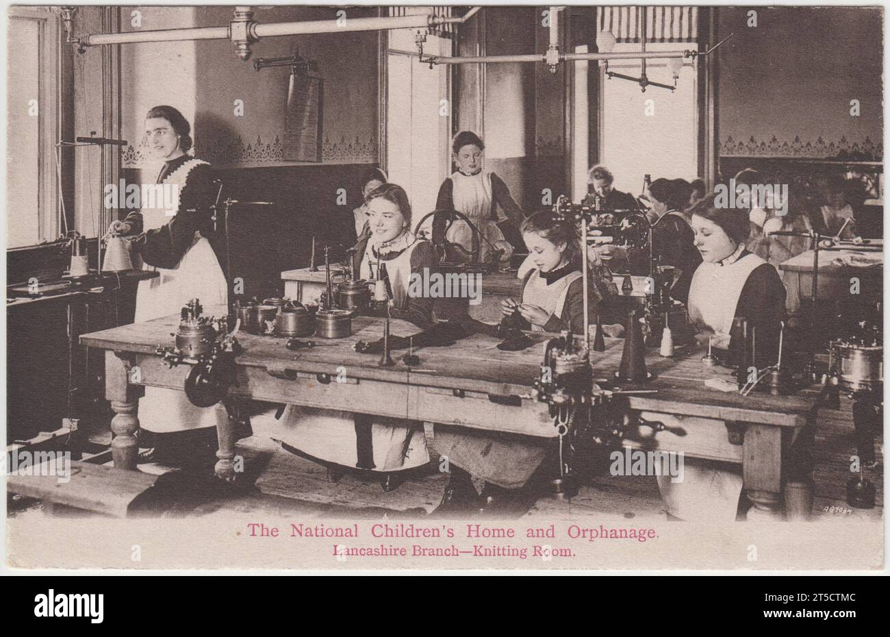 Le National Children's Home and orphelinat, Lancashire Branch, Knitting Room. Carte postale du début du 20e siècle produite dans le cadre de la campagne de financement du NCH. Il montre des filles dans des robes et des tabliers travaillant dans des machines à tricoter sur des bancs. Banque D'Images