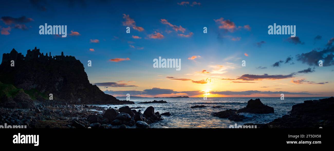 Ruines du château de Dunluce silhouettées par le soleil couchant sur la côte irlandaise, comté d'Antrim, Irlande du Nord Banque D'Images