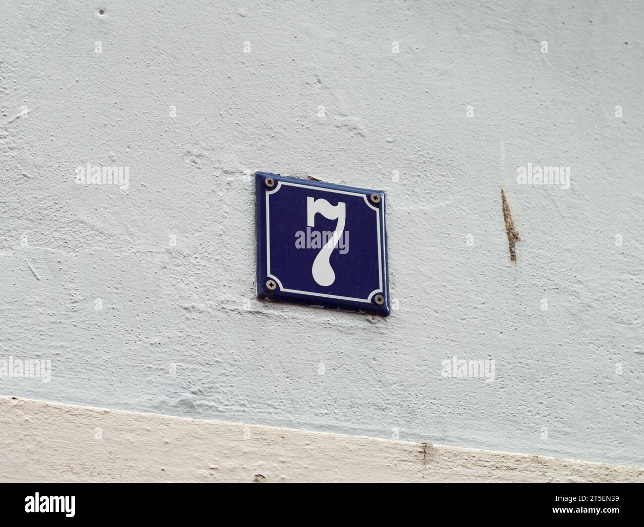 Numéro 7 sur un mur extérieur de la maison. La plaque métallique est émaillée et de couleur bleue. Le design très vintage et rétro. Le sept est aussi un nombre chanceux Banque D'Images