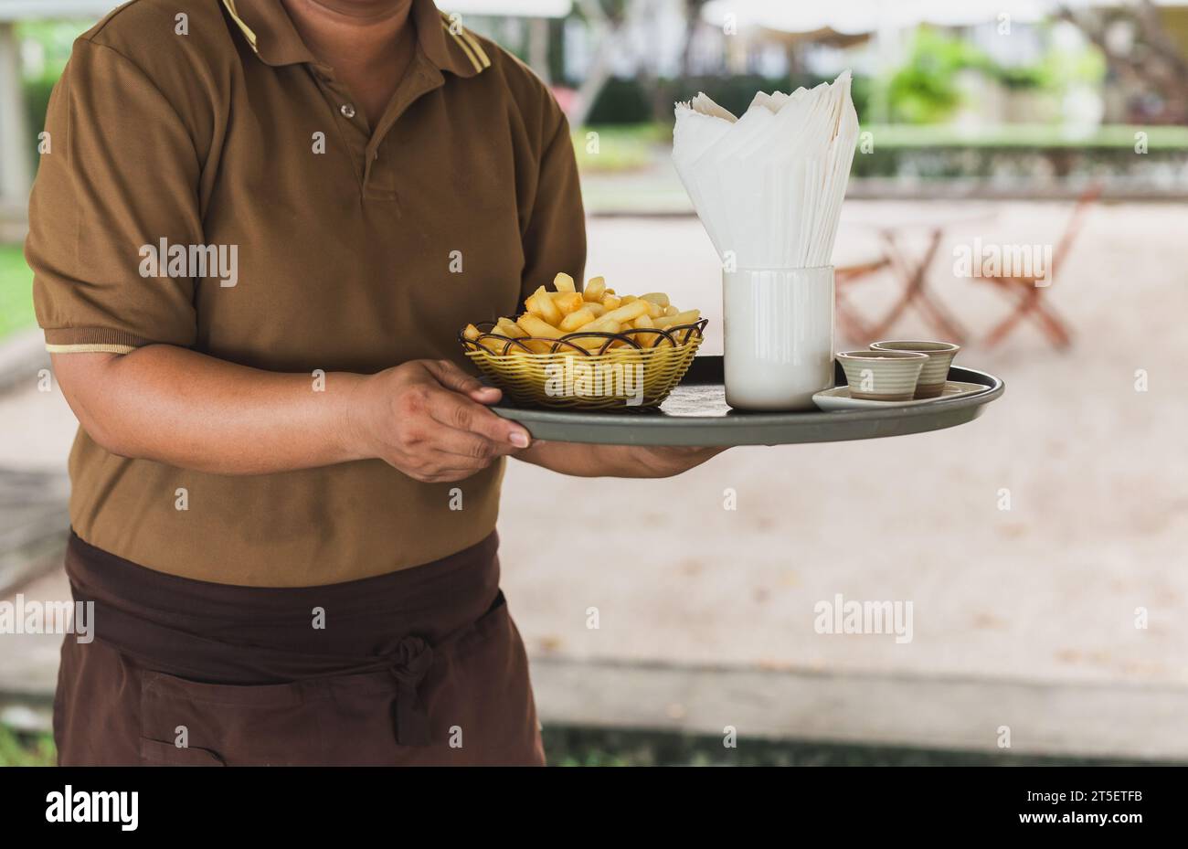 Serveuse servant des frites sur plateau au restaurant à l'extérieur. Banque D'Images