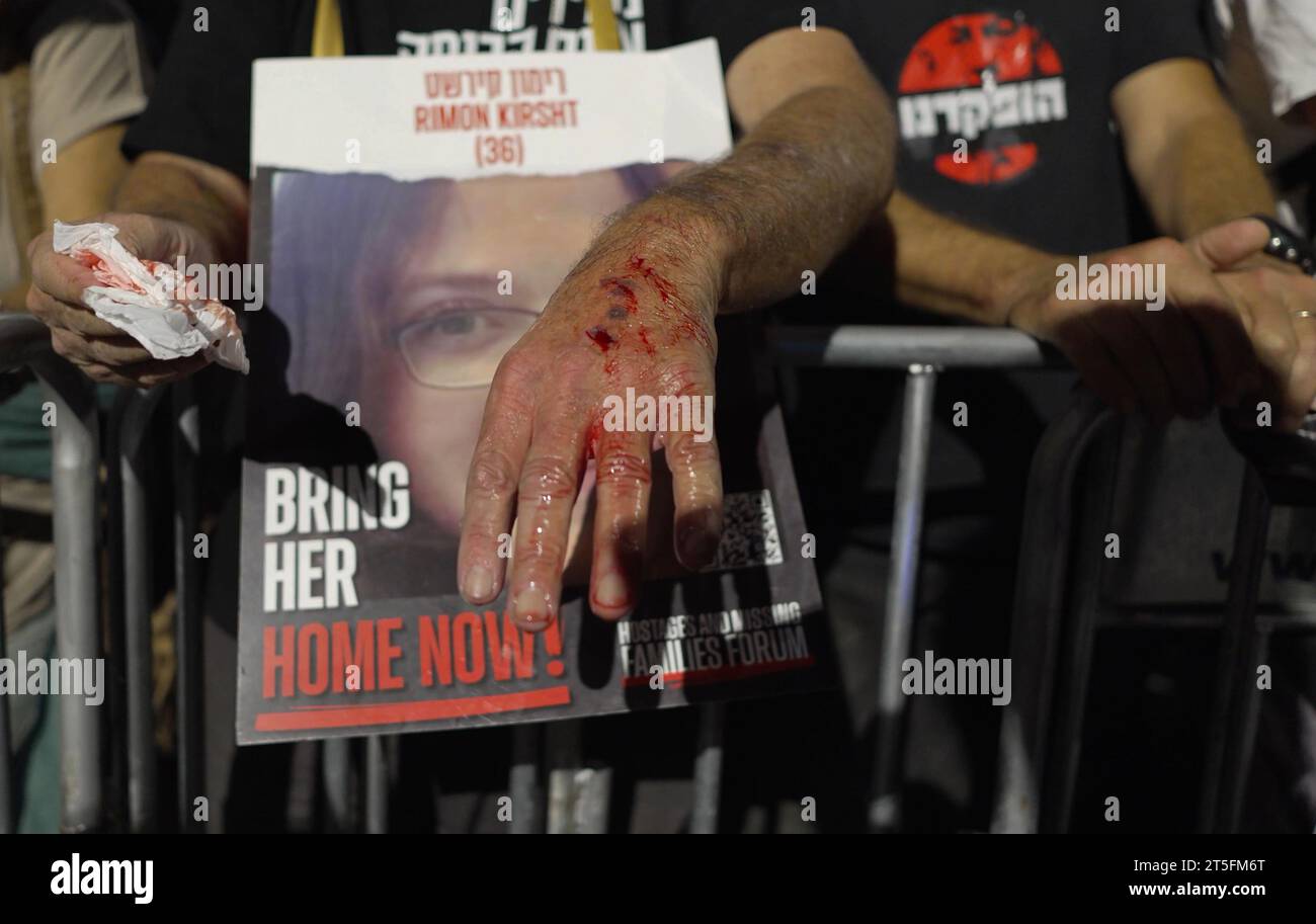 Un manifestant blessé à la main à la suite d'affrontements avec la police tient une pancarte avec la photo d'une israélienne retenue en otage par le Hamas lors d'une manifestation près de la maison privée du Premier ministre Benjamin Netanyahu, rue Azza, l'appelant à démissionner en réponse à l'attaque meurtrière du Hamas dans le sud d'Israël il y a quatre semaines, le 4 novembre 2023 à Jérusalem Israël. Banque D'Images Un manifestant blessé à la main à la suite d'affrontements avec la police tient une pancarte avec la photo d'une israélienne retenue en otage par le Hamas lors d'une manifestation près de la maison privée du Premier ministre Benjamin Netanyahu, rue Azza, l'appelant à démissionner en réponse à l'attaque meurtrière du Hamas dans le sud d'Israël il y a quatre semaines, le 4 novembre 2023 à Jérusalem Israël. Banque D'Images