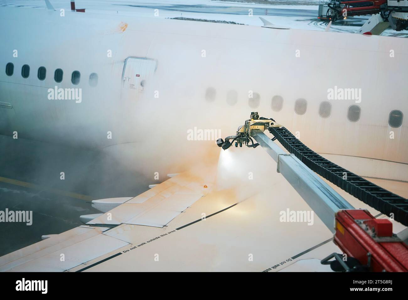 Dégivrage de l'aile d'avion avant le décollage. Hiver nuit glaciale et service au sol à l'aéroport. Banque D'Images