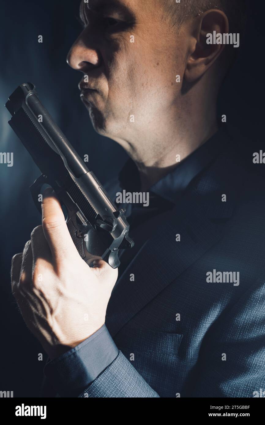 Espion thriller mafia boss assasin portrait photo en costume tenant pistolet. Banque D'Images