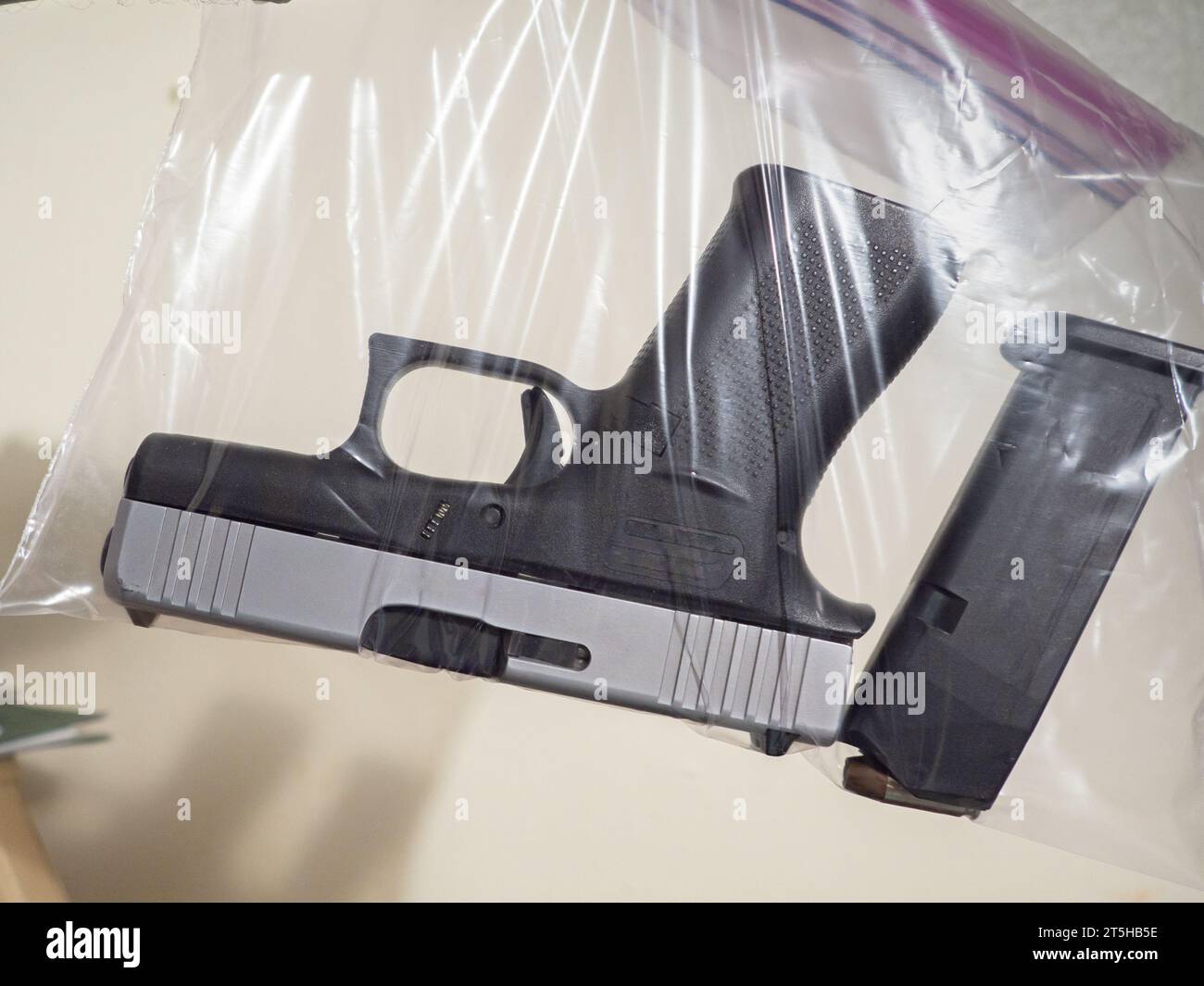 Photographie d'une main tenant un sac de videns contenant un pistolet et un clip. Banque D'Images