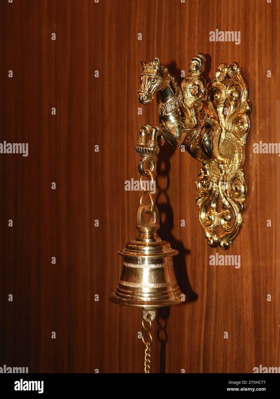 une sonnerie de cloche en bronze suspendue à une sculpture de guerrier sur un cheval fixé sur un mur en bois brun Banque D'Images