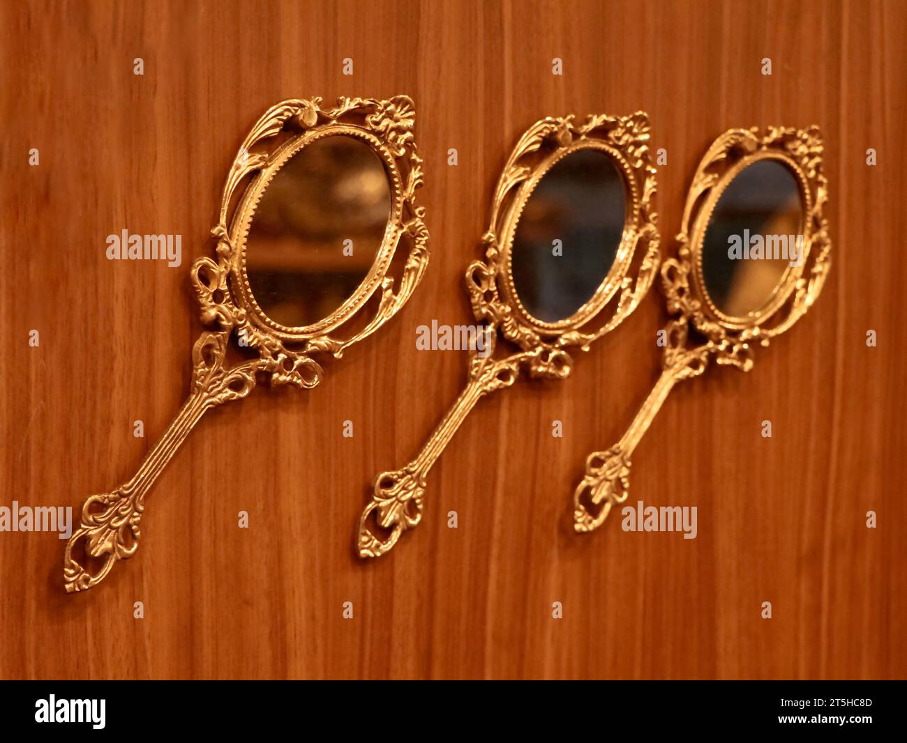 trois miroirs à main ronds dorés vintage fabriqués en bronze conservés pour être exposés sur un mur en bois à l'intérieur d'une boutique traditionnelle d'artisanat et de souvenirs Banque D'Images