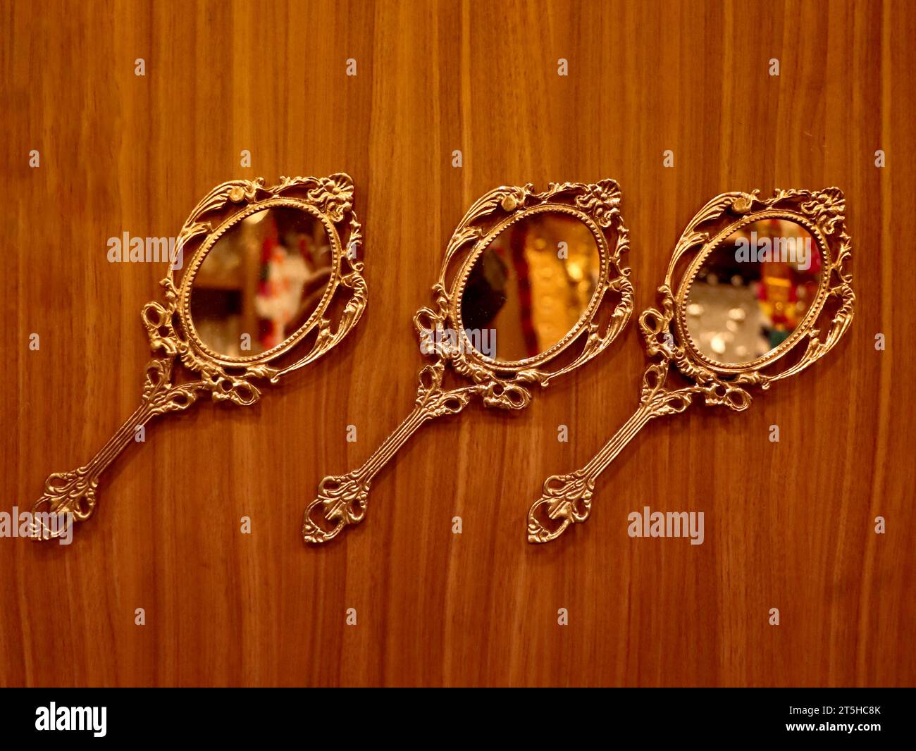 trois miroirs à main ronds dorés vintage fabriqués en bronze conservés pour être exposés sur un mur en bois à l'intérieur d'une boutique traditionnelle d'artisanat et de souvenirs Banque D'Images