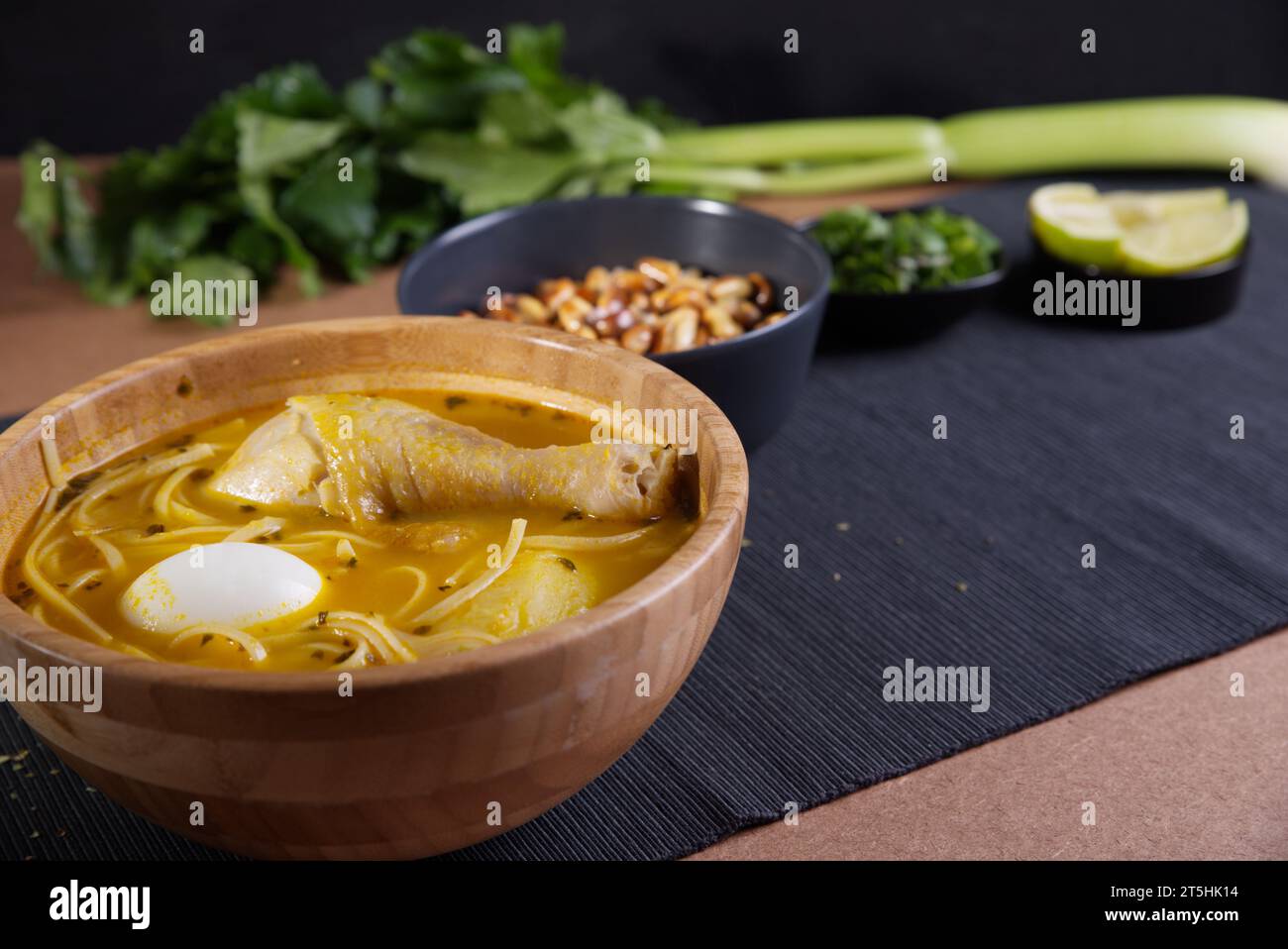 Plat typiquement péruvien connu sous le nom de soupe au poulet, dans un bol en bois avec citron et ciboulette. Banque D'Images