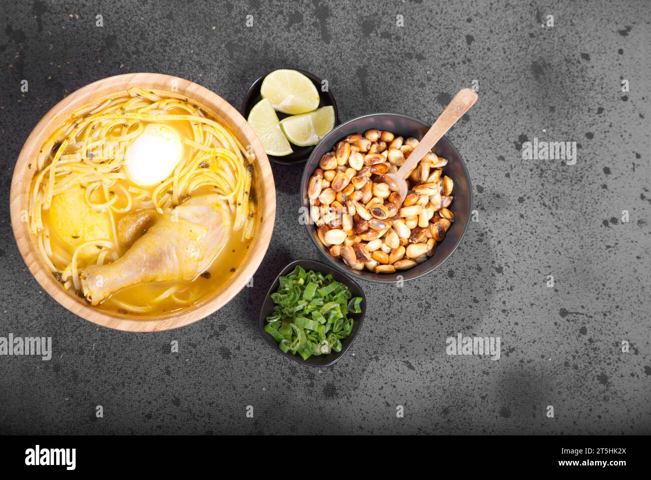 Plat typiquement péruvien connu sous le nom de soupe au poulet, dans un bol en bois avec citron et ciboulette. Banque D'Images