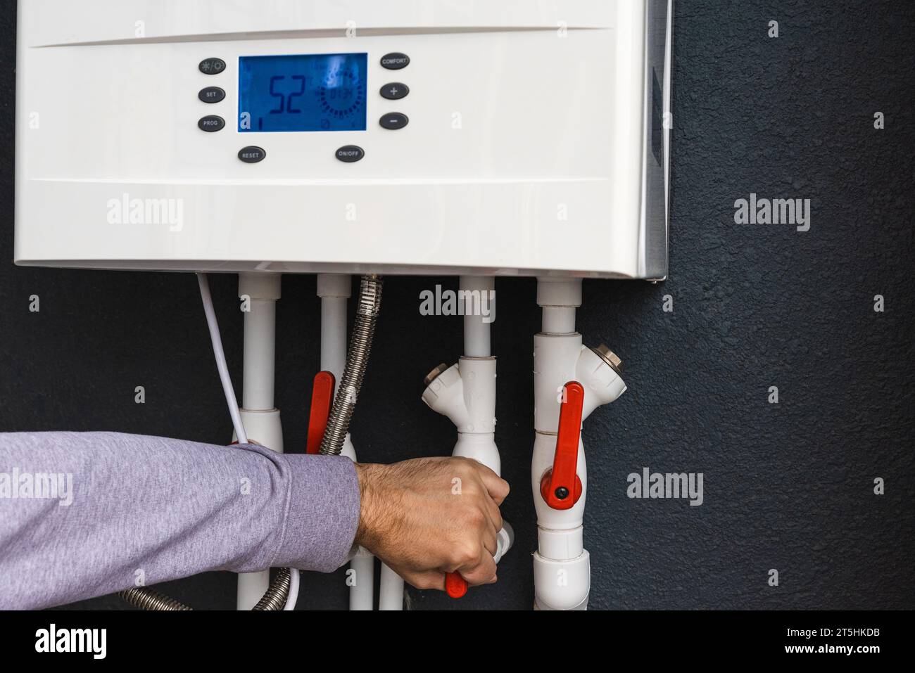 Main d'œuvre télécommande ou installation d'une chaudière à gaz à double circuit pour le chauffage à la maison et le chauffage à l'eau en hiver. Concept d'économie d'énergie et d'économie de chaleur Banque D'Images