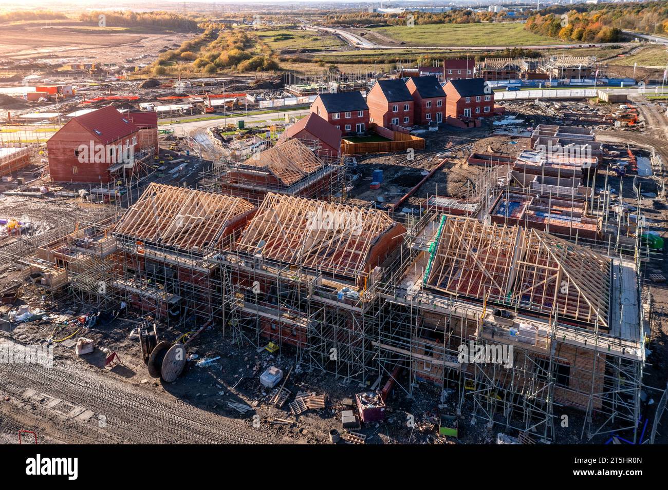 Vue aérienne d'un chantier de construction avec de nouvelles maisons écoénergétiques construites avec les chevrons de toit exposés et entourés par un échafaudage avec co Banque D'Images